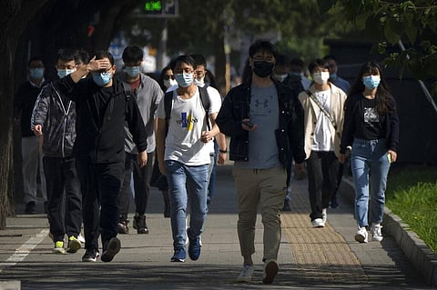 Commuters wearing face masks walk toward the central business district from a subway station that has not been closed in Beijing, Thursday, May 5, 2022. (Photo | AP)