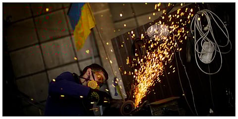 A volunteer shapes metal plates with an angle grinder at a facility producing material for Ukrainian soldiers in Zaporizhzhia. (Photo | AP)