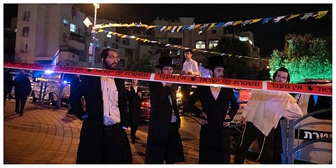 Ultra-Orthodox Jews stand behind police tape after a stabbing attack in the town of Elad, Israel, Thursday, May 5, 2022. (Photo | AP)