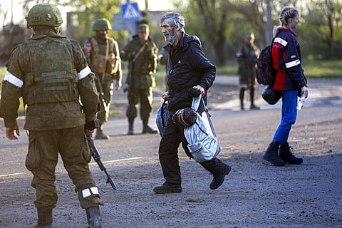 A man, who left a shelter in the Metallurgical Combine Azovstal, walks to a bus between servicemen of Russian Army and Donetsk People’s Republic militia in Mariupol. (Photo | AP)