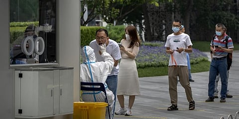 A worker wearing a protective suit swabs a man's throat for a COVID-19 test at a coronavirus testing site in Beijing, Saturday, June 11, 2022. (Photo | AP)