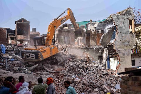 Bulldozer being used to demolish the 'illegally constructed' residence of Javed Ahmed, a local leader who was allegedly the key conspirator of violent protests. (Photo | PTI)