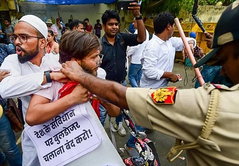 Police personnel detain protestors during a protest against the demolition of 'illegally constructed' houses in Uttar Pradesh, in New Delhi. (Photo | PTI)
