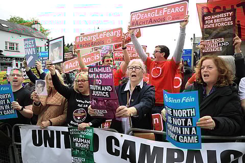 Demonstrators hold up signs including in Irish reading 'Red with Anger, Act now', as they protest outside Hillsborough Castle. (Photo | AP)