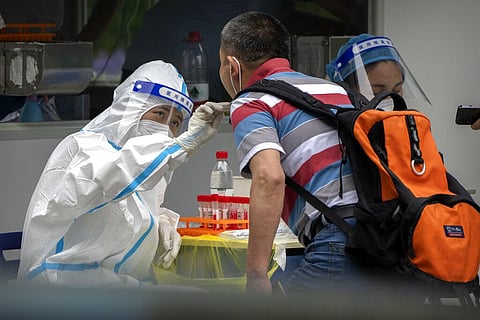 A worker wearing a protective suit swabs a man's throat for a COVID-19 test at a coronavirus testing site in Beijing, Saturday, June 11, 2022.(Photo | AP)
