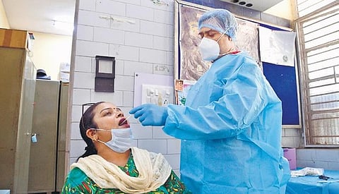 A health worker collects a swab sample of a woman for Covid-19 test, at state transport bus stand in Delhi. (Photo | Shekhar Yadav)