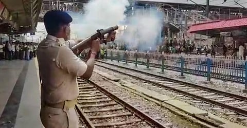 Police personnel use tear gas to disperse protestors during their demonstration against 'Agnipath' scheme, at Ara Railway Junction in Bhojpur. (Photo | PTI)