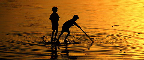 A silhouette of two boys seen playing by standing on a cardboard box inside water at Vaigai River in Madurai. (File photo| KK Sundar, EPS))
