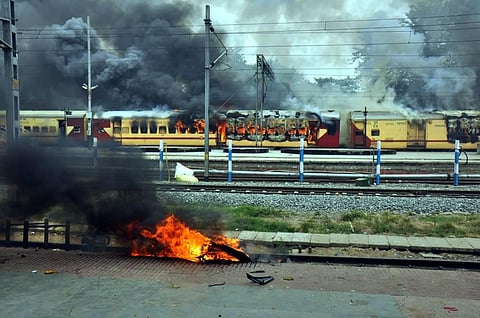 A train set on fire by a crowd in protest against the Centre's Agnipath scheme, at Danapur Railway station, near Patna. (Photo | PTI)