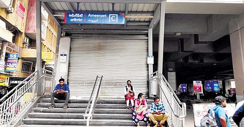 Passengers sit on the steps of the Ameerpet Metro Station after services were suspended on Friday