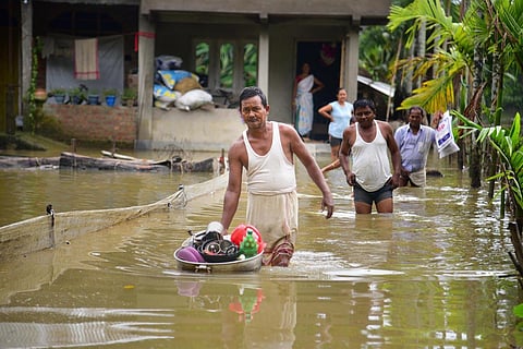 Villagers with their belongings move to a safer place from a flood-affected area after heavy rains, in Nagaon district of Assam. (Photo | PTI)