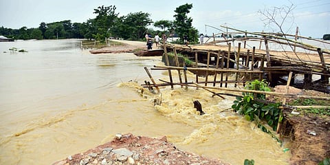 Villagers use a temporary bamboo bridge to cross flooded area at Kampur village, in Nagaon. (Photo| PTI)