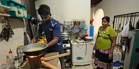 Miraj Madusanka, left, helps his mother Sriyani, light a firewood hearth at their house in Colombo, Sri Lanka. (Photo | AP)