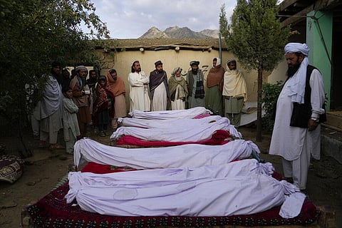 Men stand around the bodies of people killed in an earthquake in Gayan village, in Paktika province, Afghanistan, Thursday, June 23, 2022.