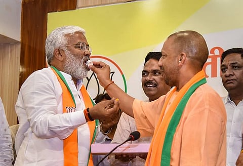 Uttar Pradesh Chief Minister Yogi Adityanath and UP BJP President Swatantra Dev Singh feed each other sweets as they celebrate the party's victory in the bypolls. (Photo | PTI)