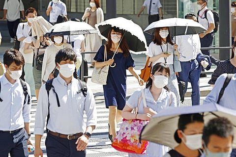 People, some of them holding parasols, cross an intersection amid heat, in Tokyo on Monday. (Photo | AP)