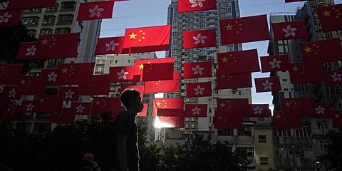 A man walks past Chinese and Hong Kong flags to celebrate the 25th anniversary of Hong Kong handover to China, in Hong Kong, Friday, June 24, 2022.(Photo | PTI)