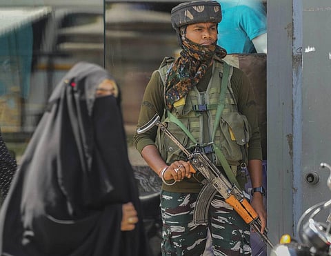 An Indian paramilitary soldier guards as a Muslim woman walks at a market in Srinagar. (Photo | AP)