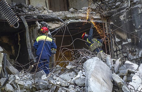 Ukrainian emergency service personnel work outside the damaged building following shelling, in Kharkiv, Ukraine. (Photo | AP)