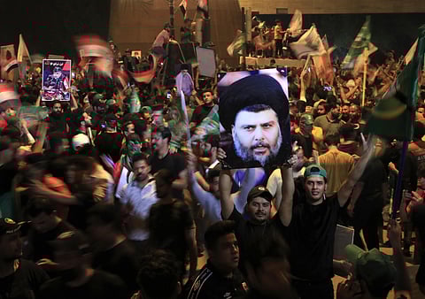 Followers of Shiite cleric Muqtada al-Sadr, on the poster, celebrate after the announcement of the results of the parliamentary elections in Tahrir Square, Baghdad, Iraq, Monday, Oct. 11, 2021. (AP)