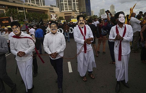 Sri Lankan protesters wear masks of president Gotabaya Rajapaksa's family members during a march demanding Gotabaya resign, at the ongoing protest site in Colombo. (Photo | AP)