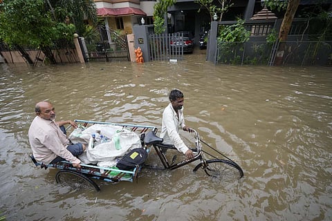 A cycle rickshaw puller transports a man through a water logged road after heavy rain lashed city on Sunday night in Ahmedabad. The waterlogged underpasses and streets of the city was flooded making commuting difficult for the residents. Ahmedabad recorded 114mm of rain between 7 pm on Sunday and Monday 10 am. (Photo | AP)