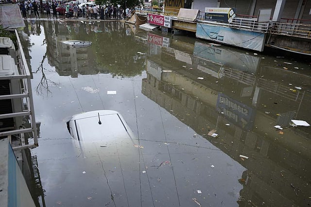 Vehicles seen submerged at a water logged shopping complex after heavy rain lashed city on Sunday night in Ahmedabad. A total of 64 people have died in Gujarat due to various rain related incidents.  (Photo | AP)