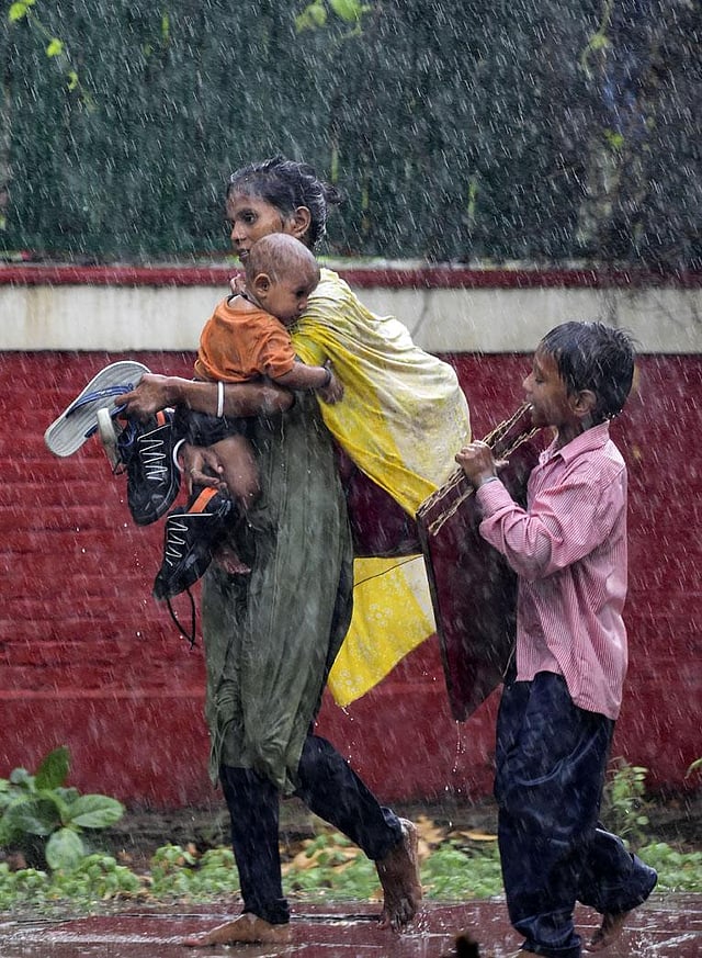 People look for shelter during monsoon rain in New Delhi. The city received its much needed respite after a week long hot and humid weather. The IMD has forecast cloudy sky for July 12 with the possibility of light rain or thundershowers with maximum and minimum  temperatures around 36 and 37 degree celsius. (Photo | PTI)