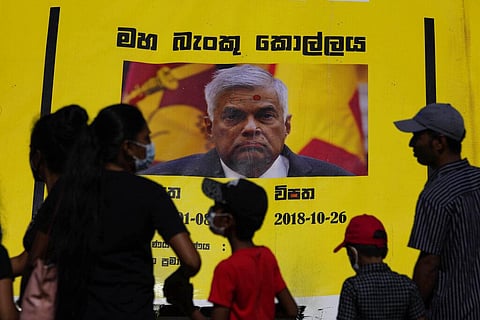 People watch propaganda materials displayed against prime minister Ranil Wickremesinghe outside president Gotabaya Rajapaksa's office. (Photo | AP)
