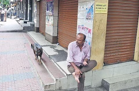 A man sits in front of a closed shop at Chamarajpet in Bengaluru. Hundreds of shops remained closed on Chamarajpet bandh called by Hindu outfits | Shriram BN