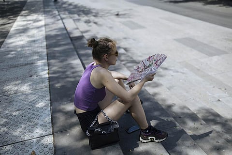 A woman uses a hand fan to cool off during a heatwave in Paris. (Photo | AP)