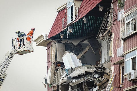 A fireman looks into the partially collapsed section of a building in China's Tianjin Municipality. (Photo |AP)