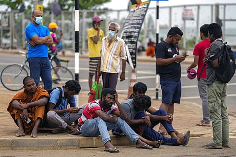 Dejected protesters sit on a street corner after they were evicted by the military from the presidential offices they had occupied for days, in Colombo. (Photo | AP)