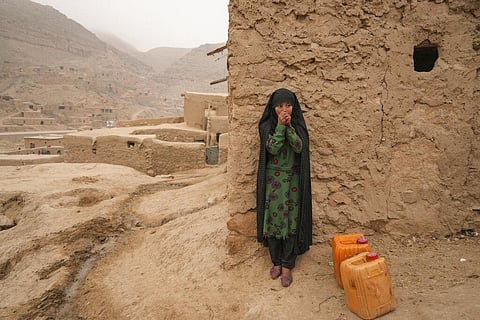 An Afghan girl warms up her hands as she is resting from carrying the water in Balucha, Afghanistan. (Photo | AP)