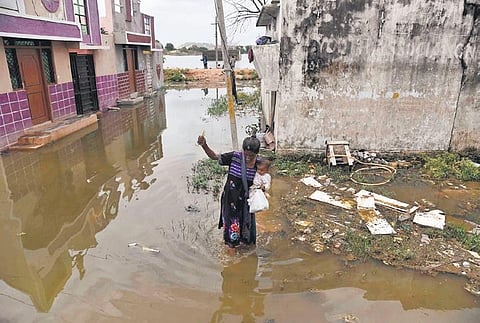 A woman carrying a child wades through the stagnated water in Osman Nagar in Hyderabad on Monday | Vinay Madapu