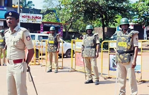 Police officials stand guard at Mangalapet on the outskirts of Mangaluru city on Friday following the murder of Mohammed Fazil, 23, at Surathkal