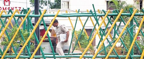 A police officer crosses a median through a damaged patch of the fence. (File photo| EPS)
