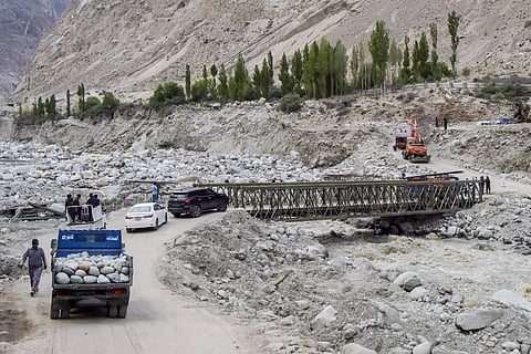People drive through a temporary bridge after the main bridge was swept away by a lake outburst because of a melting glacier, in Hassanabad village of Pakistan's Gilgit-Baltistan region. (Photo | AFP)
