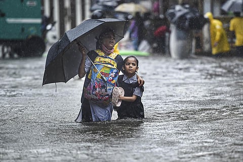 A school girl with her guardian wades through a flooded street following heavy monsoon rains, in Mumbai. (Photo | PTI)