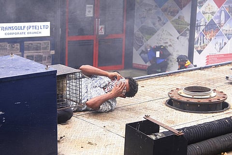 A Sri Lankan man covers his face after a tear gas shell is fired by police on an attempt to disperse the protesters near him. (Photo | AP)