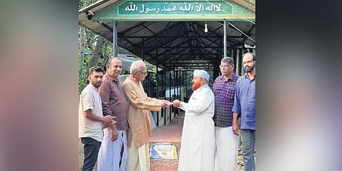 Temple committee members handing over money to the mosque committee.