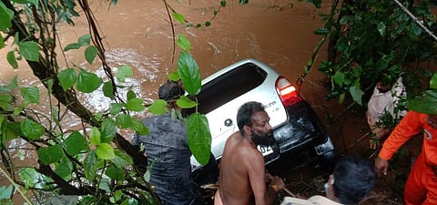 Locals help fire officials pull the car out of the canal in Kerala.