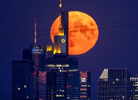The full moon rises behind the buildings of the banking district in Frankfurt, Germany. (Photo | AP)