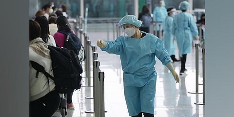 Workers wearing protective gear direct arriving passengers to quarantine hotels in the Hong Kong International Airport. (Photo | AP)