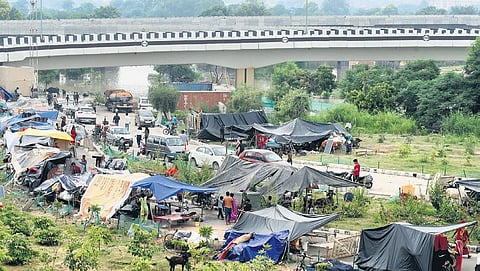 Locals with their belongings took shelter on an elevated ground due to rise in water level of Yamuna River. (Photo | Parveen Negi, EPS)