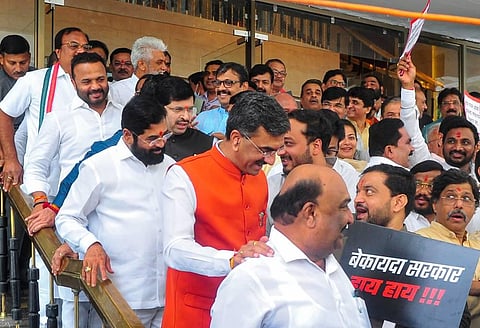 Maharashtra Chief Minister Eknath Shinde looks at a placard displayed by an opposition member as he arrives for the first day of Monsoon Session of Maharashtra Assembly, in Mumbai. (Photo | PTI)