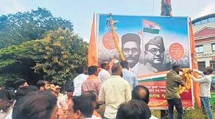 BJP Backward Classes Morcha National General Secretary Yashpal Suvarna garlands the flex of VD Savarkar at Brahmagiri Circle in Udupi on Wednesday