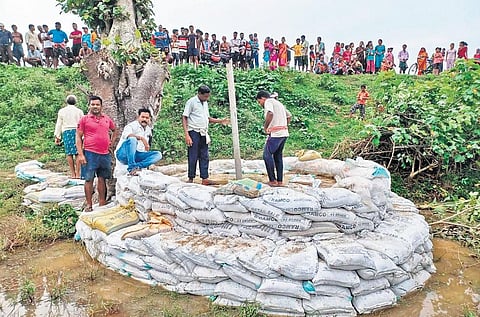 Locals packing a breach in river embankment with sand bags at Sankilo | Express