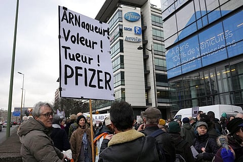 A demonstrator holds a placard reading 'Scammer, thief, killer, Pfizer' during a protest against the vaccine pass and vaccinations to protect against COVID-19 in front of the Pfizer headquarters(AP)