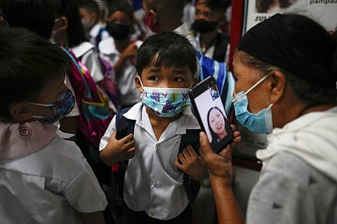 A boy talks to his mother from a smartphone during the opening of classes at the San Juan Elementary School in metro Manila, Philippines on Monday, Aug. 22, 2022. (Photo | AP)